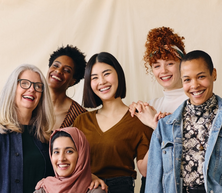 A group of seven women of different ages and races smile together